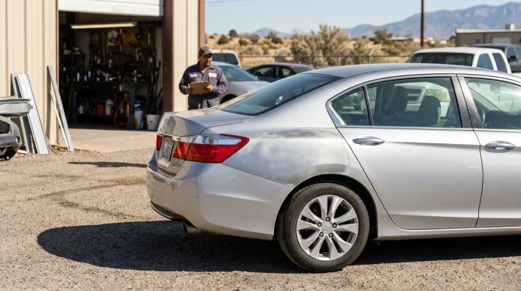 mechanic holding clipboard inspecting sedan outside auto repair shop